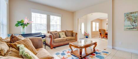 A living room with a piano, a sofa, a coffee table, and a dining area with chairs.