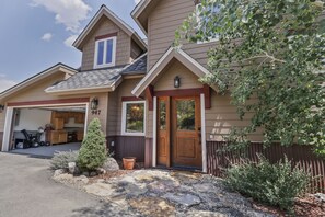 A two-story house with a garage, a front door, and a small tree in the front yard. - 947 Blue Ridge 4 Bedroom Home (Silverthorne)