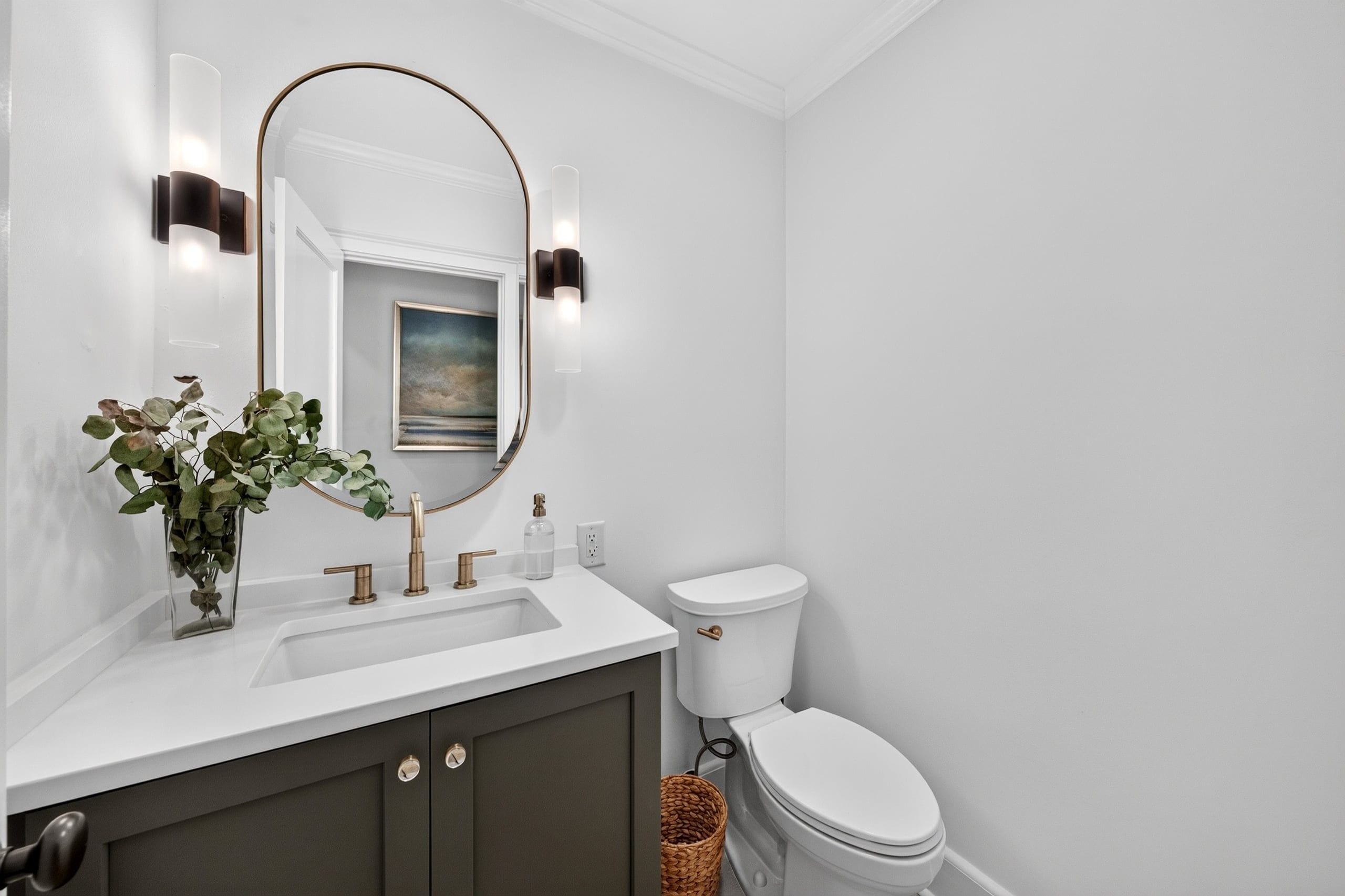 A bathroom with a white sink, a toilet, and a mirror with a gold frame.