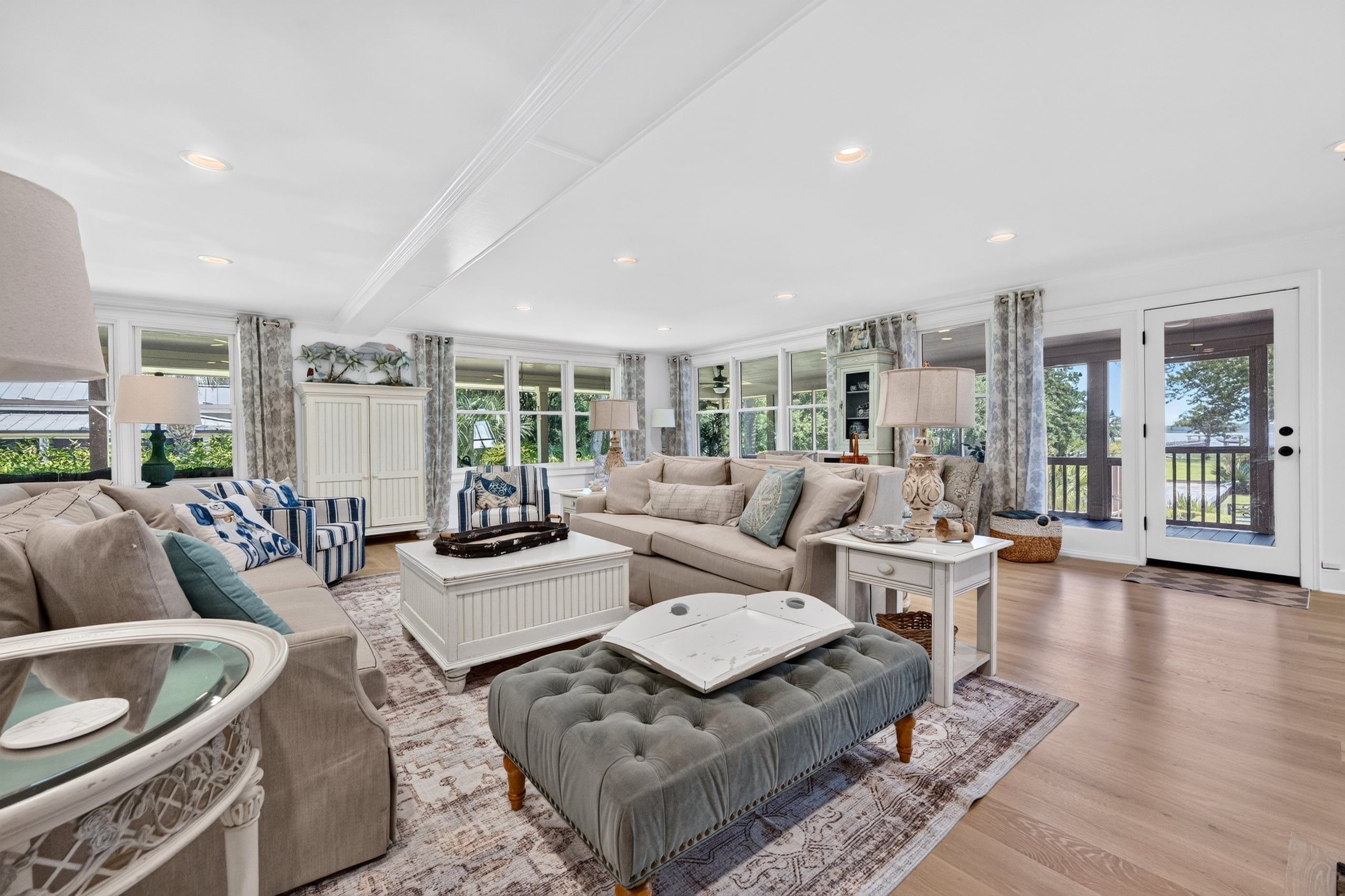A spacious living room with a large window, a sofa set, a coffee table, and a glass-top table.