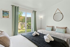 A hotel room with a bed, two bedside tables, a nightstand, a lamp, a mirror, and a view of the outdoors. - Villa with views over the Gulf of St-Tropez (Grimaud)