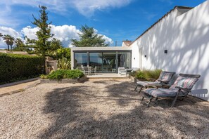 A modern house with a patio area featuring outdoor furniture and a gravel ground. - Villa with views over the Gulf of St-Tropez (Grimaud)