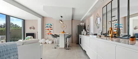 Una cocina moderna con armarios blancos, una isla grande y un área de comedor con taburetes de bar.