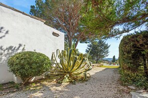 A garden pathway leading to a white building with a small tree and a large agave plant. - Villa with views over the Gulf of St-Tropez (Grimaud)