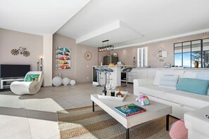 A modern living room with a white sofa, a coffee table with books, and a TV. - Villa with views over the Gulf of St-Tropez (Grimaud)