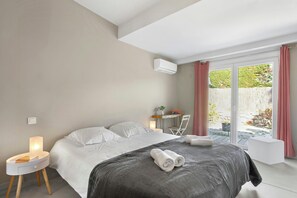 A bedroom with a bed, bedside tables, a desk, and a view of the outdoors. - Villa with views over the Gulf of St-Tropez (Grimaud)
