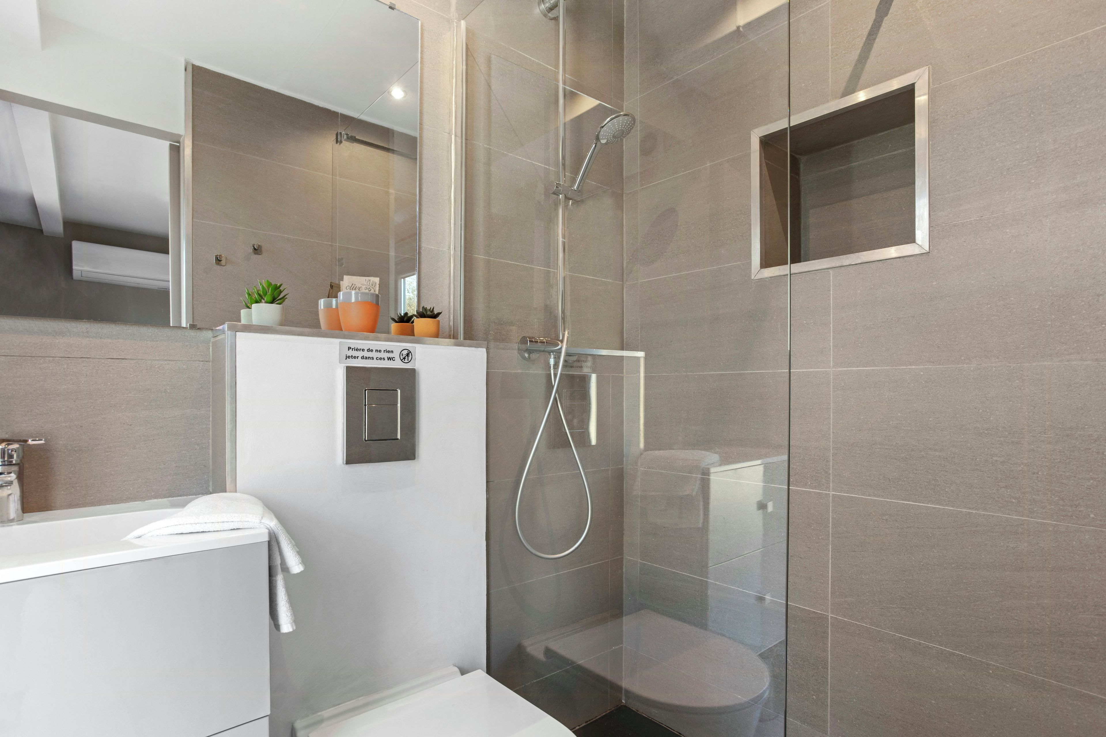 A modern bathroom with a glass-enclosed shower, a toilet, and a sink.