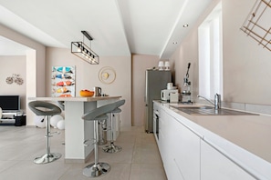 A modern kitchen with a bar area, stainless steel appliances, and a minimalist design. - Villa with views over the Gulf of St-Tropez (Grimaud)