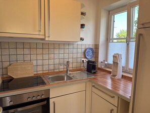 A kitchen with a stove, sink, and cabinets.