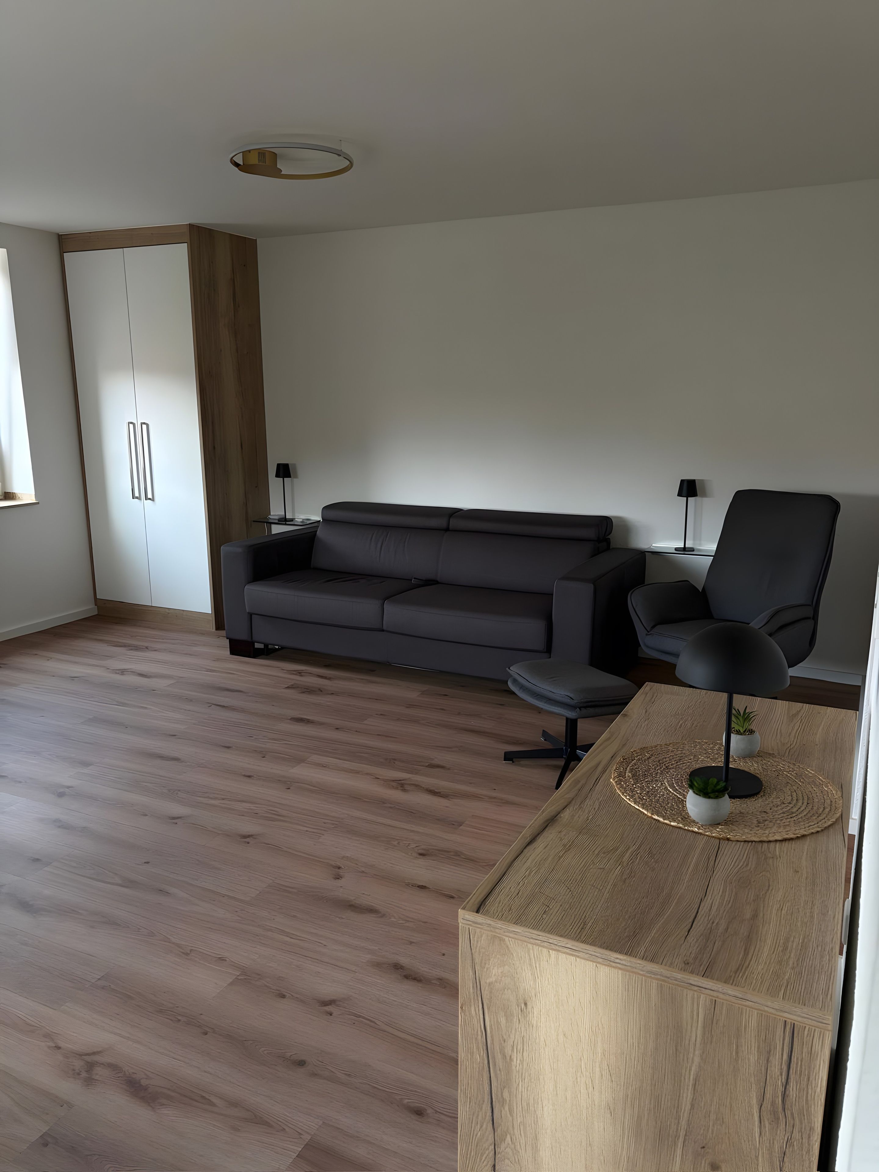 A modern living room with a grey sofa, a black armchair, and a wooden coffee table.