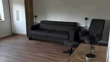 A modern living room with a grey sofa, a black armchair, and a wooden coffee table.