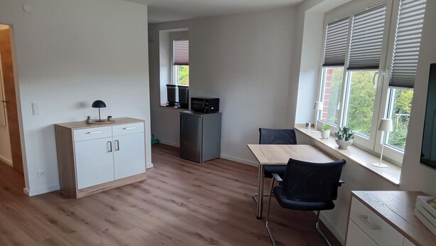 A compact kitchen with a dining area, a microwave, and a refrigerator. - Apartment in A Hotel 'Blickallee' (Havixbeck)