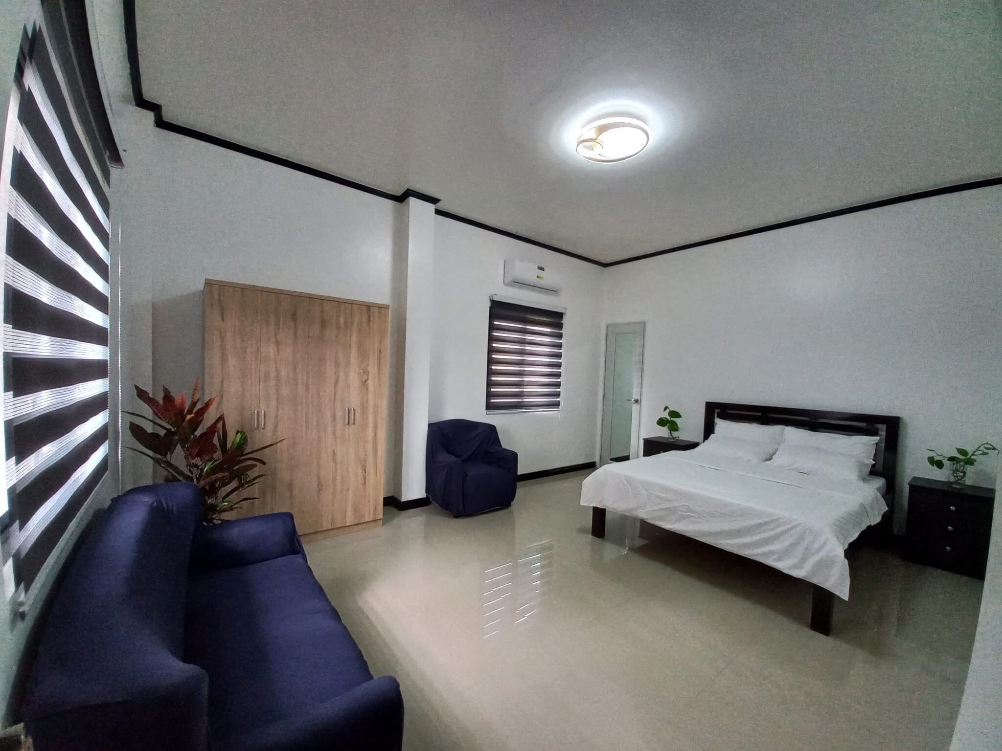 A hotel room with a bed, a wardrobe, a seating area, and a ceiling light.