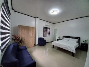 A hotel room with a bed, a wardrobe, a seating area, and a ceiling light.
