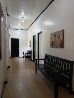 A hallway with a bench, a door, and a painting on the wall.