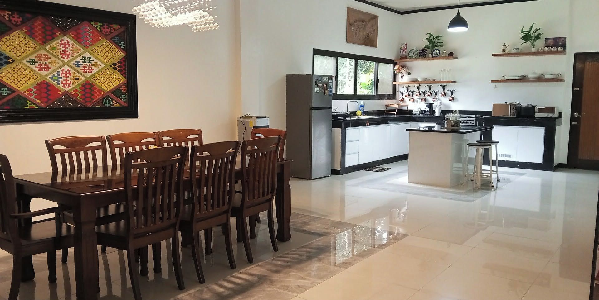 Una cocina moderna con una isla central, una mesa de comedor de madera y sillas.
