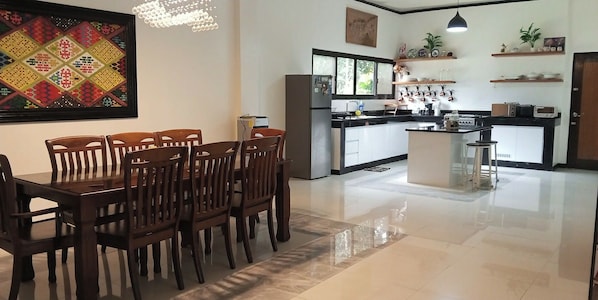 A modern kitchen with a central island, wooden dining table, and chairs.