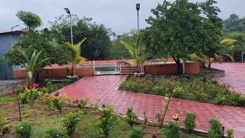 A garden area with a paved walkway, a small bridge, and various plants and flowers.