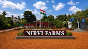 A sign for Nirvi Farms with a flag in the background. - Nirvi Farms (Chinchawali Tarf Atone)