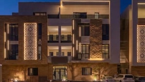 Un hotel de varios pisos con un diseño moderno, con balcones y motivos decorativos en la fachada.