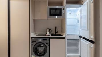 Una kitchenette funcional con lavadora, microondas y refrigerador.