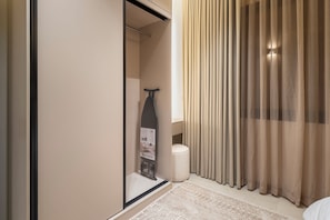 Habitación de hotel con puerta corrediza, una mesita con una botella, un objeto decorativo y una alfombra estampada.
