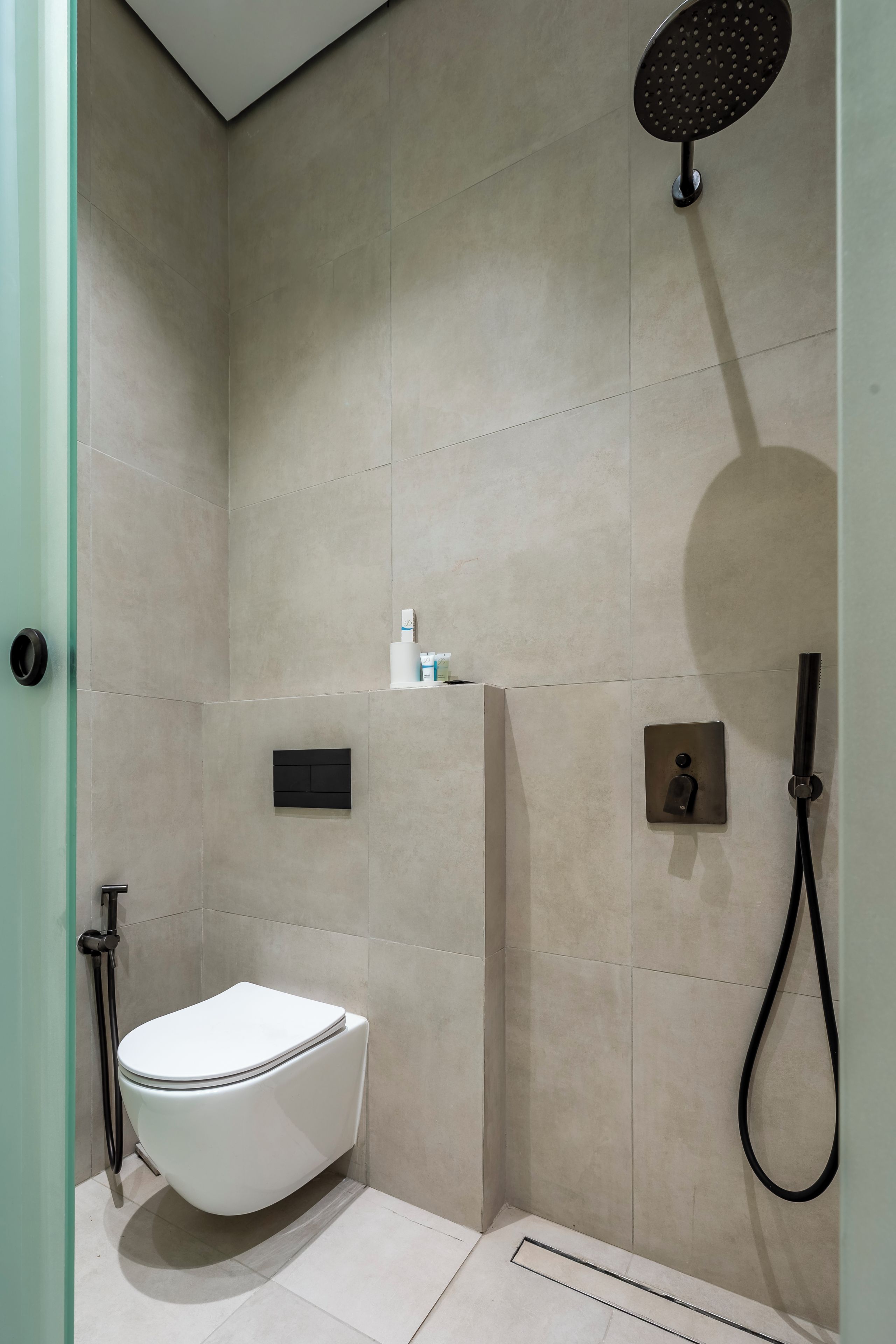 Un baño moderno con inodoro, ducha y panel de control.