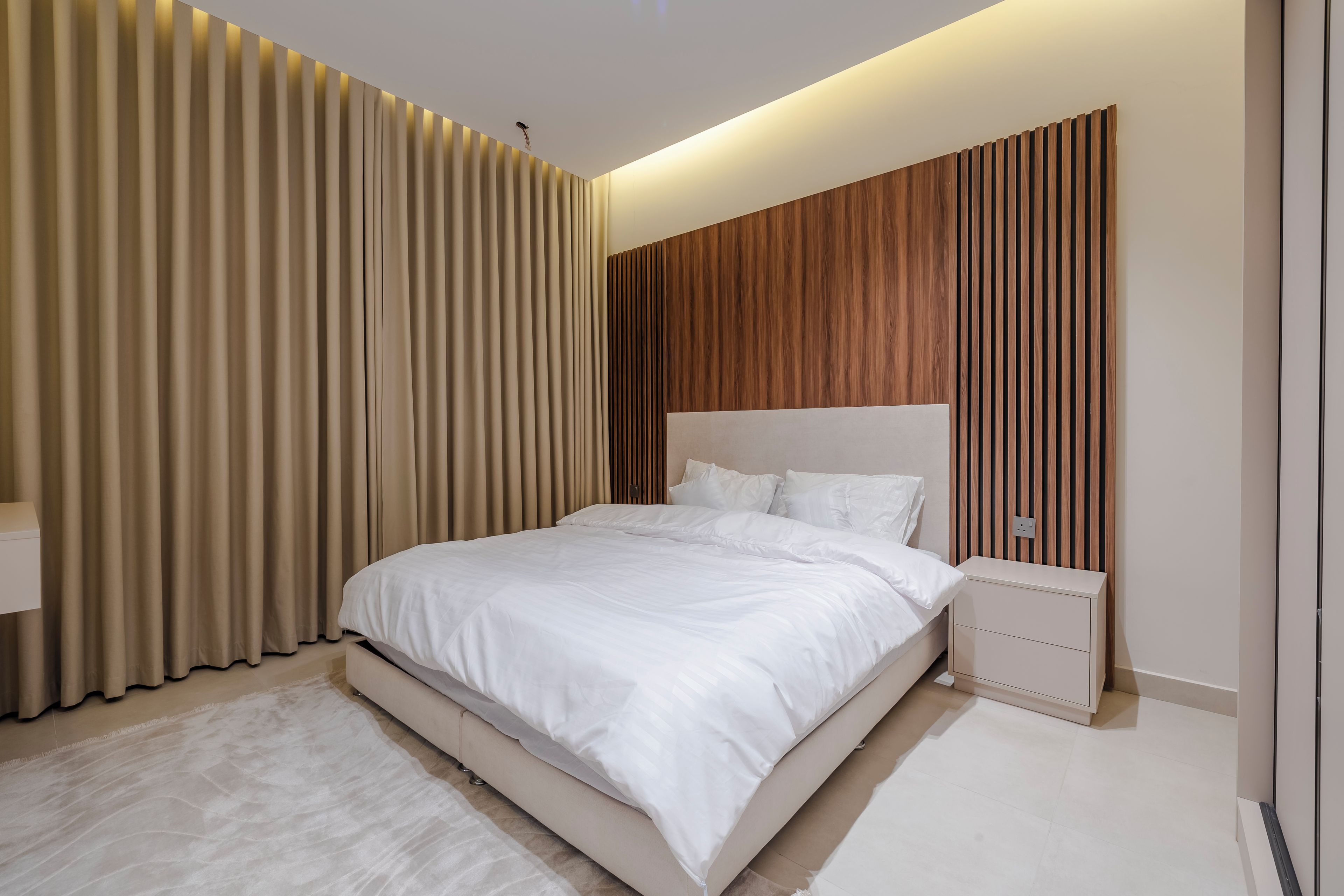 Un dormitorio moderno con una cama grande, una mesita de noche y un panel de pared de madera.
