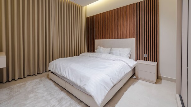 Un dormitorio moderno con una cama grande, una mesita de noche y un panel de pared de madera.