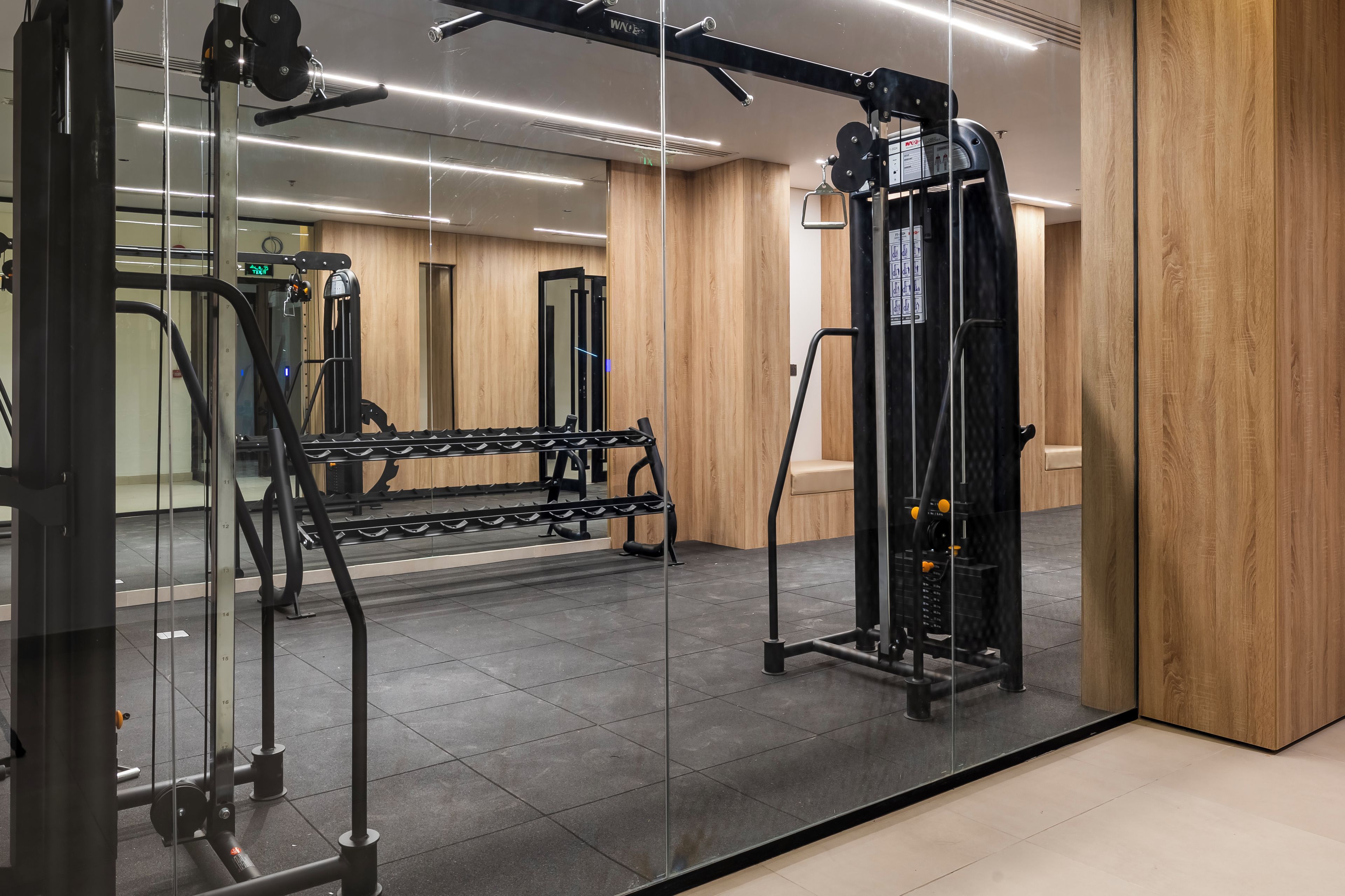 A gym with exercise equipment, a bench, and a mirror.