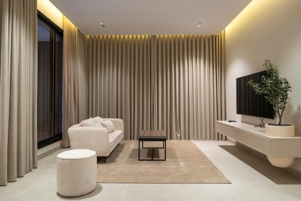 A modern living room with a sofa, a coffee table, a television, and a plant.