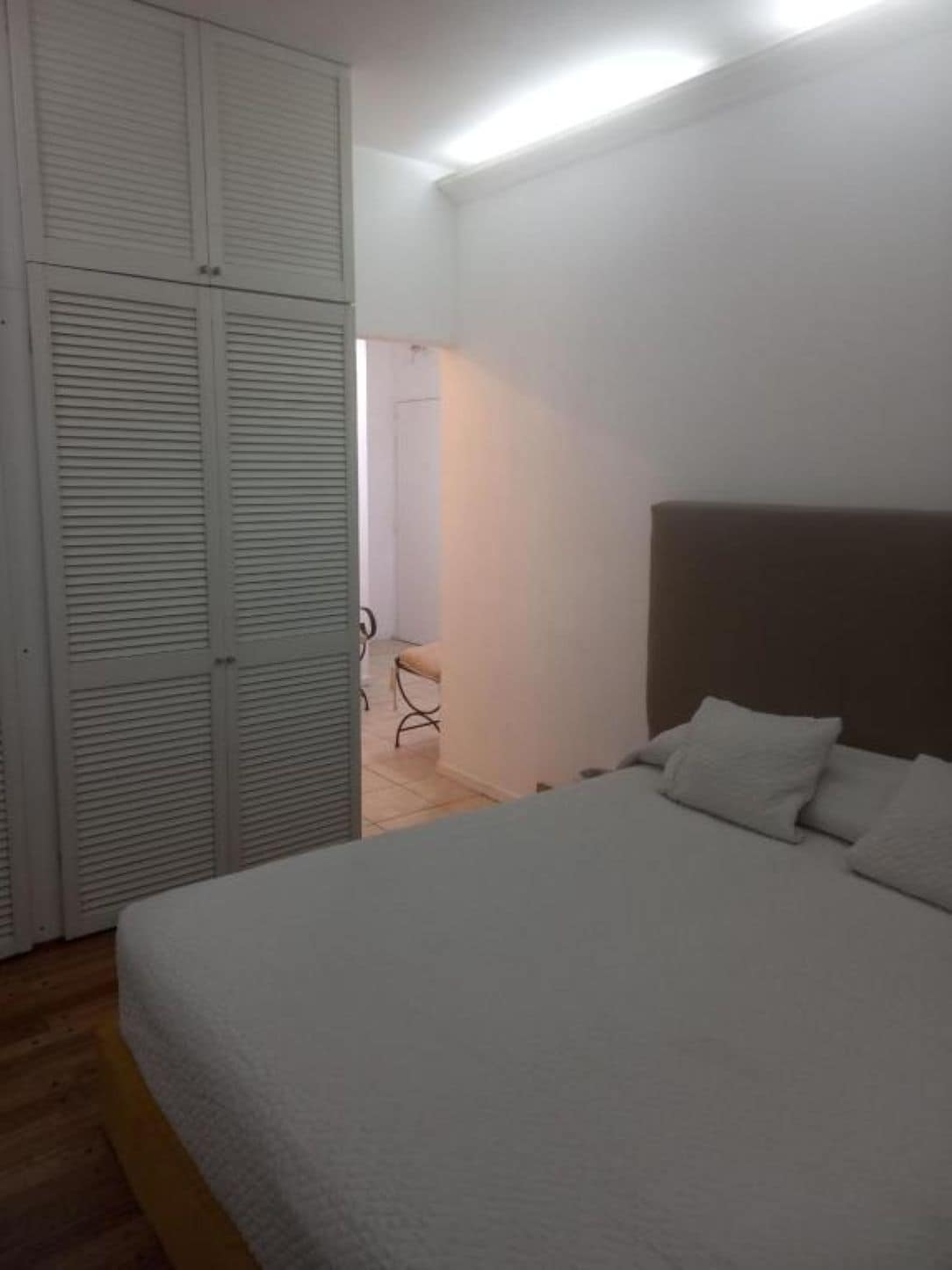 Een slaapkamer met een bed, een kast en een stoel.