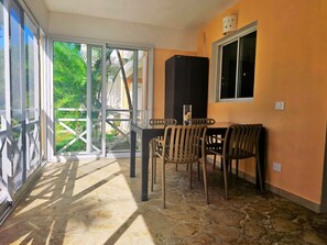 Une pièce comprenant une table à manger et des chaises, un meuble noir et une fenêtre.