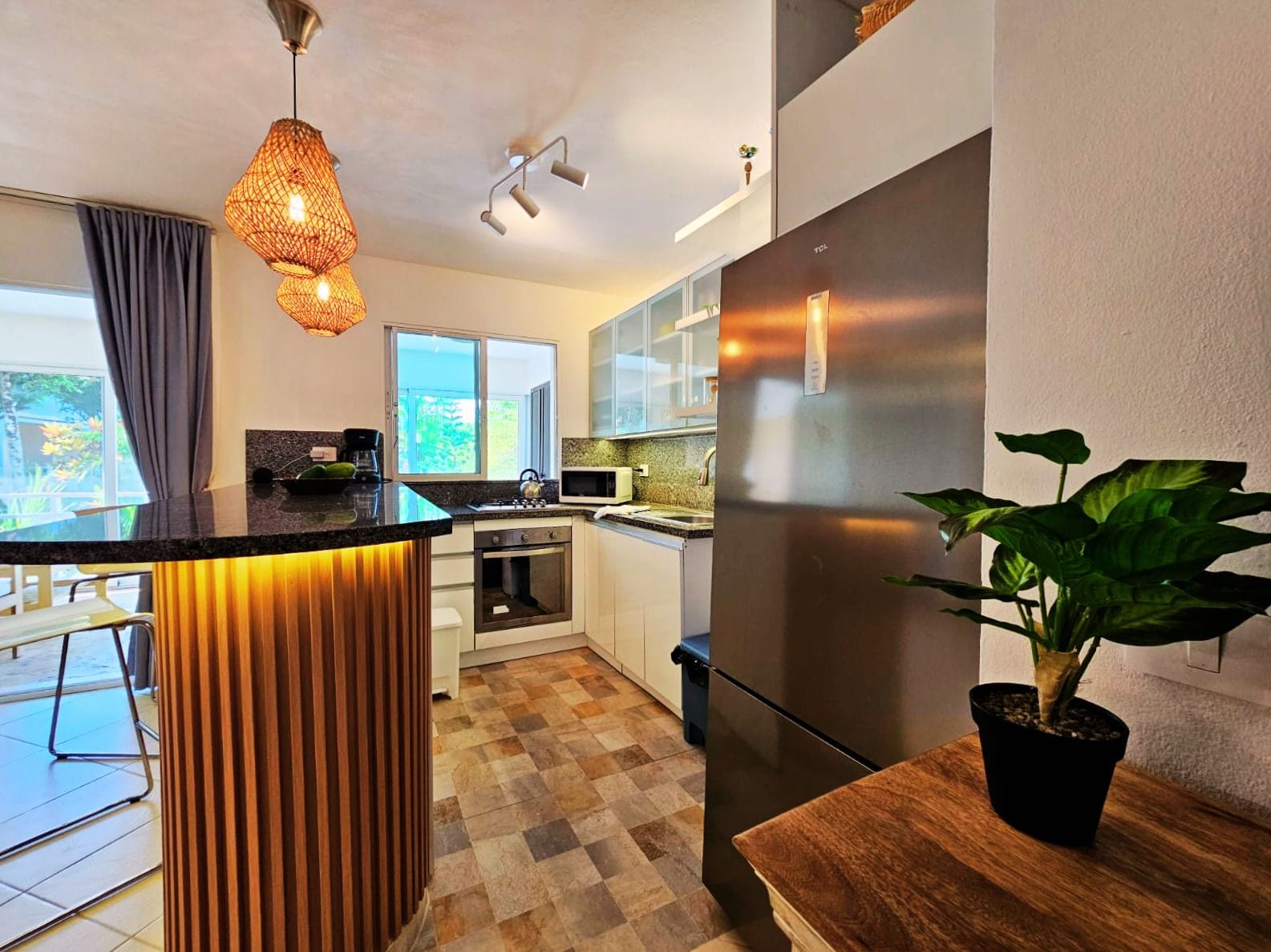 A modern kitchen with a central island, stainless steel appliances, and a large window.