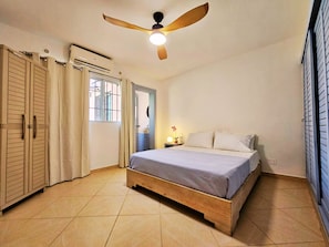 Ein Schlafzimmer mit einem Bett, einem Deckenventilator, einem Fenster und einem Kleiderschrank.
