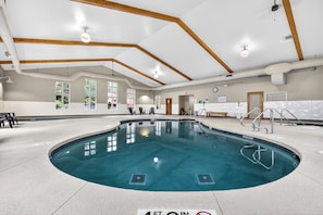 Ein Hallenbad mit 1,20 Meter flachem Einstieg, Holzbalken an der Decke und großen Fenstern.