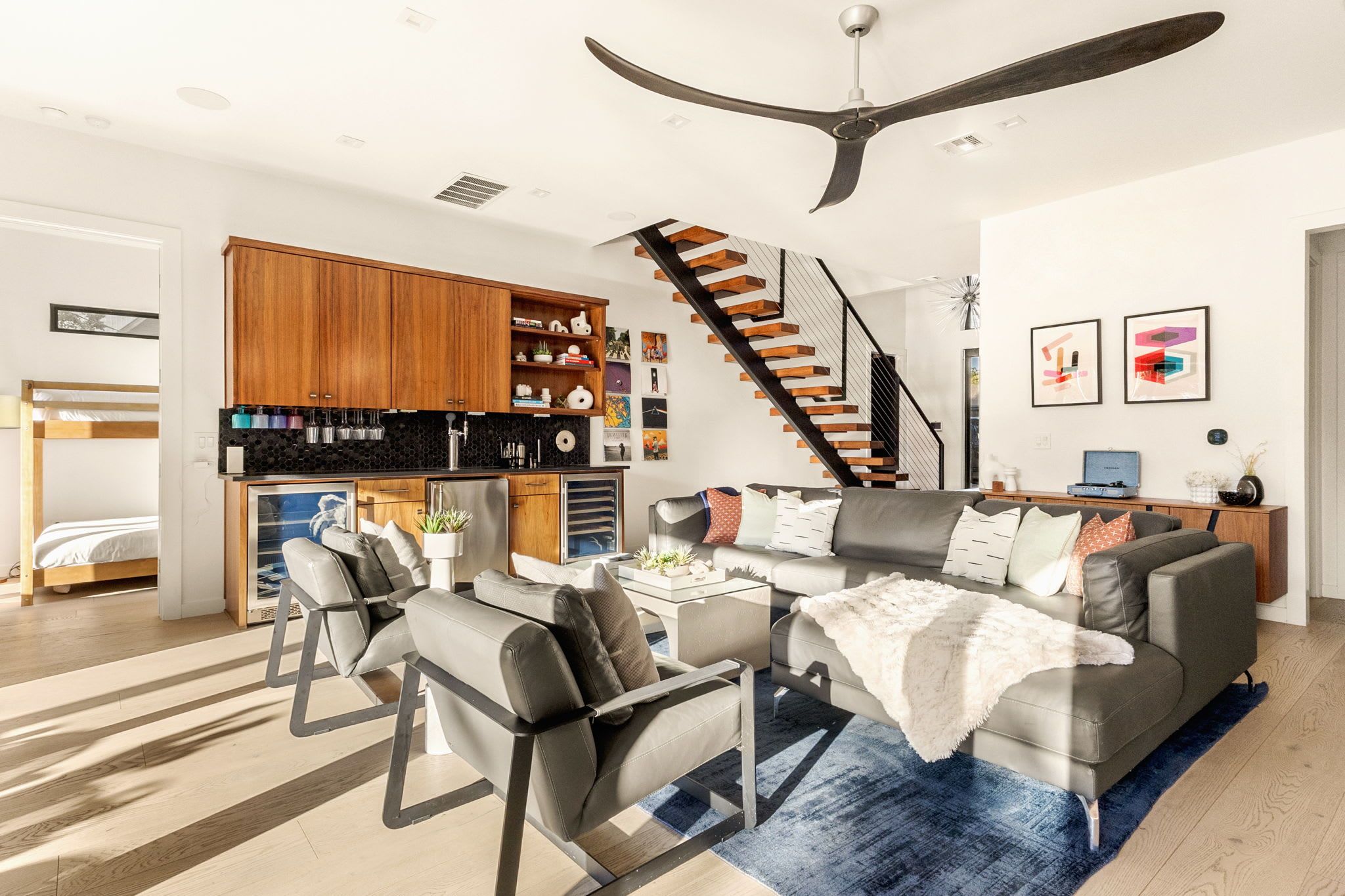 A modern living room with a sofa, chairs, a coffee table, and a staircase.