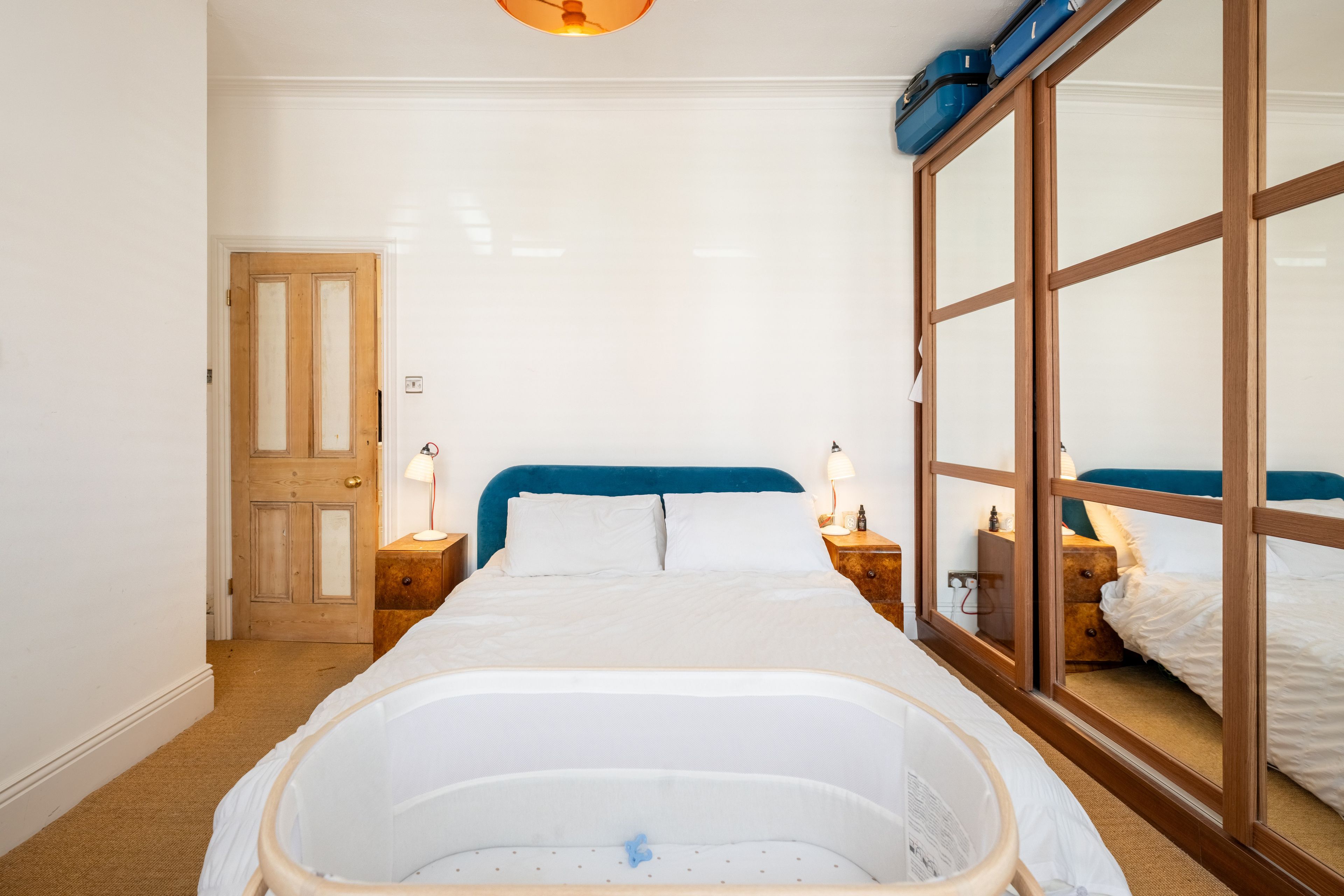 Une chambre à coucher avec un grand lit, une armoire en bois et une porte.