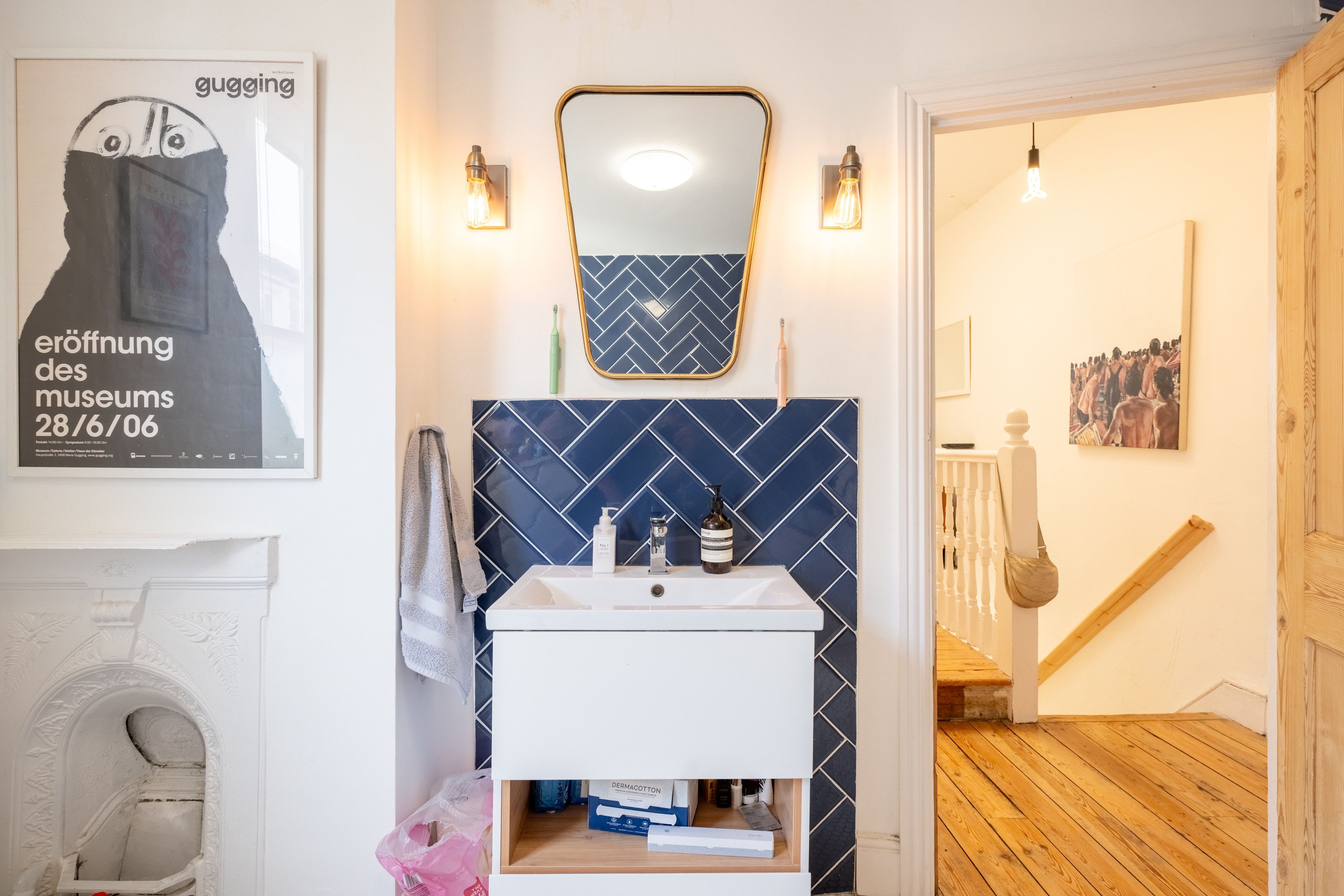 A bathroom with a white sink, a mirror with a gold frame, and a blue herringbone-patterned wall.
