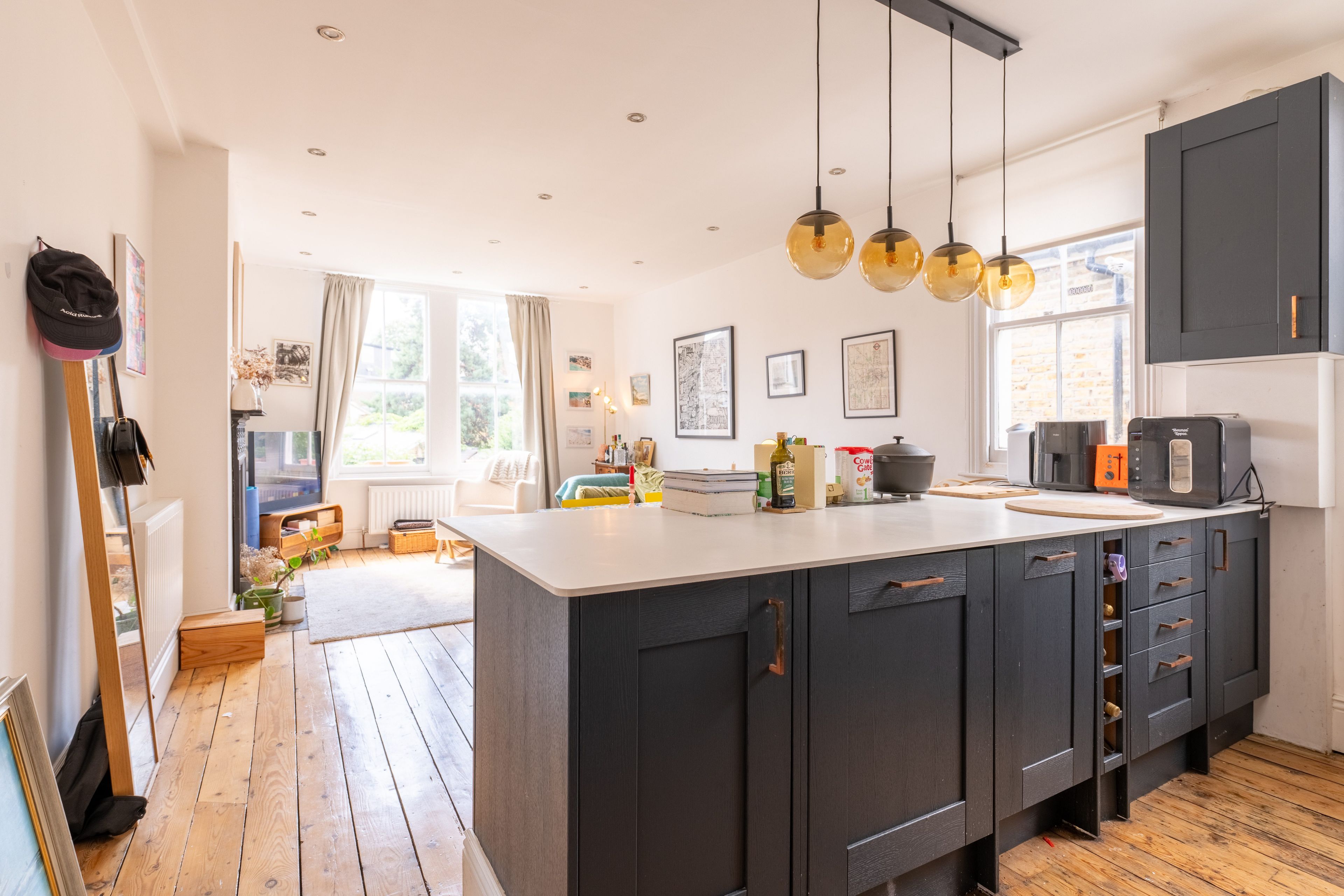 A modern kitchen with a central island, dark cabinetry, and pendant lighting.