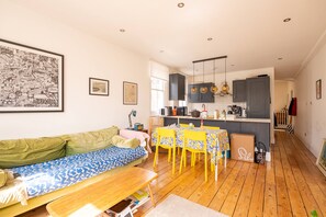 Ein modernes Wohnzimmer mit Sofa, Esstisch und Küchenzeile.
