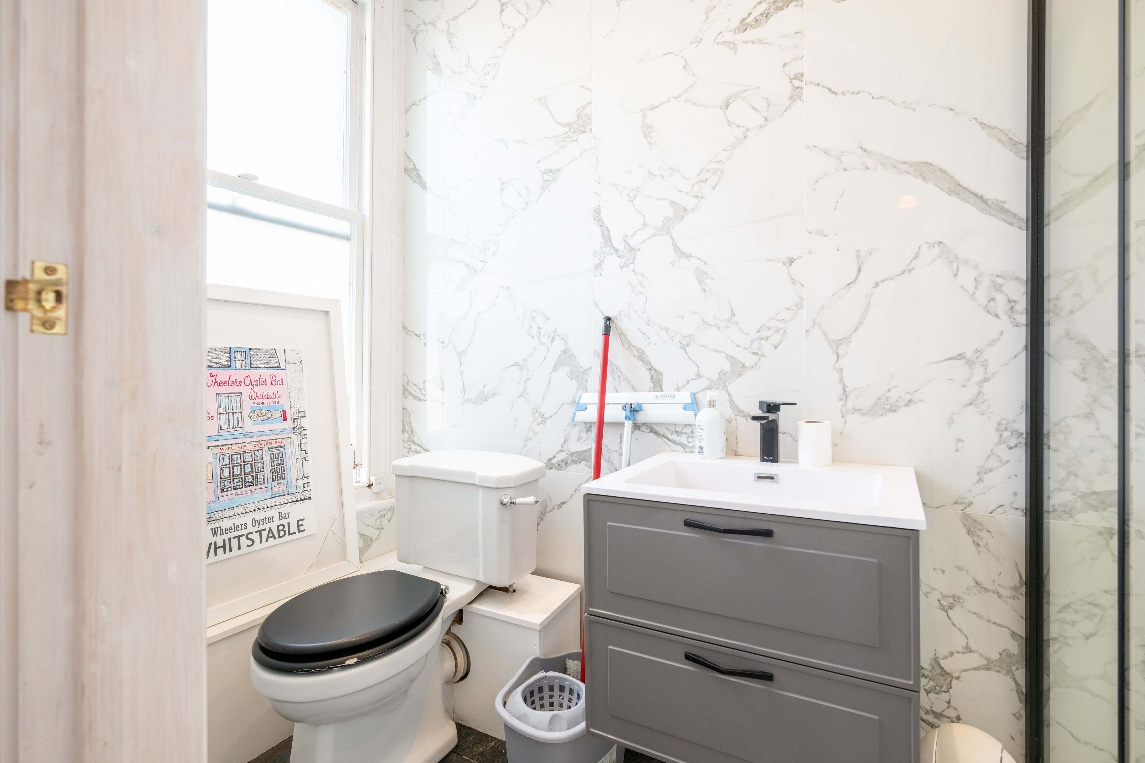 Een badkamer met toilet, wastafel en prullenbak.