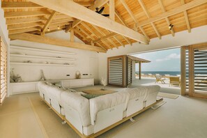 A spacious room with a large bed, a seating area, and a view of the sea. - Kas Secreto – An Exclusive Oceanfront Escape Villa in Bonaire (Kralendijk)