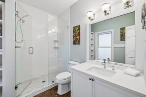 A modern bathroom with a glass-enclosed shower, a white toilet, and a vanity with a large mirror. - Steps to Coquina Pool & Short Walk to the Gulf—Elegant Retreat w/Patio & Bikes (Rosemary Beach)