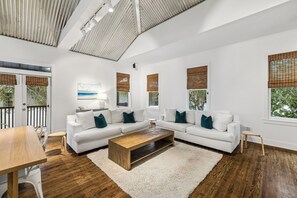 Ein modernes Wohnzimmer mit einem Ecksofa, einem Holztisch und einem Essbereich mit Tisch und Stühlen.