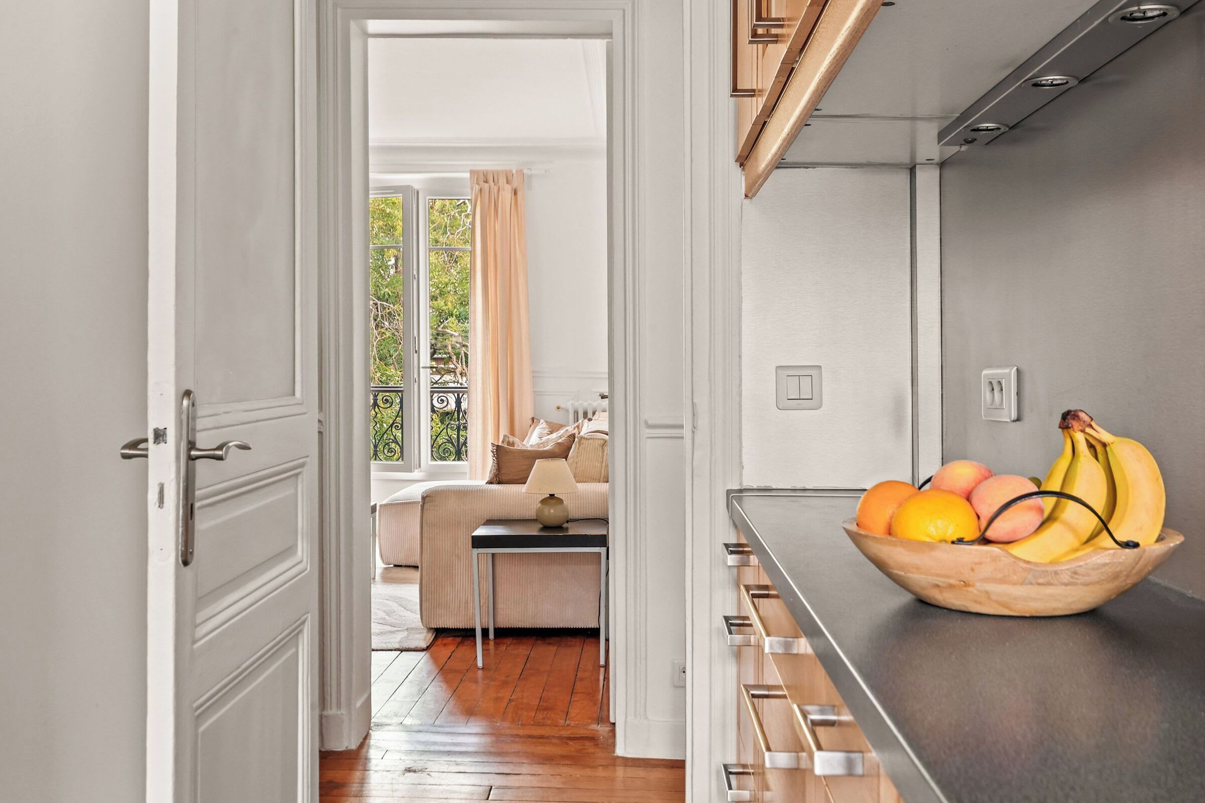 Una cocina moderna con un bol de frutas de madera sobre la encimera.