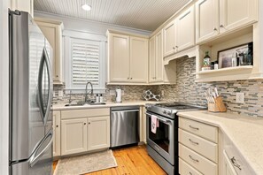 A modern kitchen with stainless steel appliances, a dishwasher, and a tiled backsplash. - Charming Two-Level Coastal Condo near the Beaufort Hotel — Great Location! (Beaufort)