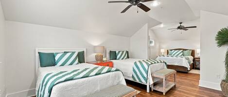 A bedroom with two beds, a ceiling fan, and a wooden bench.