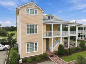 A two-story building with a balcony and a covered porch area. - Charming Two-Level Coastal Condo near the Beaufort Hotel — Great Location! (Beaufort)