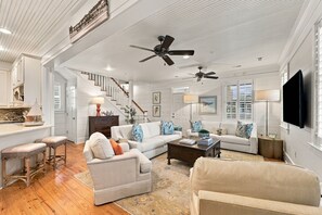A spacious living room with a high ceiling, two sofas, a coffee table, and a television. - Charming Two-Level Coastal Condo near the Beaufort Hotel — Great Location! (Beaufort)